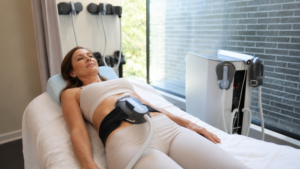Woman receiving Emsculpt for abs treatment in med spa room